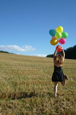 SpaceNet Award Mädchen mit Hellium Luftballons auf einer Wiese mit Bergen im Hintergrund